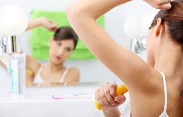 Young beautiful caucasian woman using deodorant