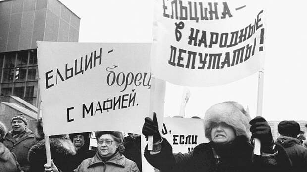 ITAR-TASS: USSR, MOSCOW. People holding banners "Yeltsin - the horror of mafia", "Yeltsin to beelected people's deputy" at the rally ahead of people's deputies of USSR pre-election meeting. (Photo ITAR-TASS/ Anatoly Morkovkin and Andrei Solovyev) Ìîñêâà. Â 1989 ãîäó íà îêðóæíîì ïðåäâûáîðíîì ñîáðàíèè ïî âûäâèæåíèþ êàíäèäàòîâ â íàðîäíûå äåïóòàòû ÑÑÑÐ ïî òåððèòîðèàëüíîìó èçáèðàòåëüíîìó îêðóãó ¹13 Êóíöåâñêîãî ðàéîíà ãîðîäà Ìîñêâû áûëè èçáðàíû êàíäèäàòàìè â íàðîäíûå äåïóòàòû Á. Áîíäàðåâ - ïåðâûé çàìåñòèòåëü ãåíåðàëüíîãî äèðåêòîðà íàó÷íî-ïðîèçâîäñòâåííîãî îáúåäèíåíèÿ "Âèëñ", Áîðèñ Åëüöèí - ïåðâûé çàìåñòèòåëü ïðåäñåäàòåëÿ Ãîññòðîÿ ÑÑÑÐ è Â. Ðîìàøêèí - ãàçîýëåêòðîñâàðùèê çàâîäà "Ýëåêòðîùèò". Íà ñíèìêå: ìèòèíã ïåðåä íà÷àëîì ñîáðàíèÿ. Ôîòî Àíàòîëèÿ Ìîðêîâêèíà è Àíäðåÿ Ñîëîâüåâà /Ôîòîõðîíèêà ÒÀÑÑ/.