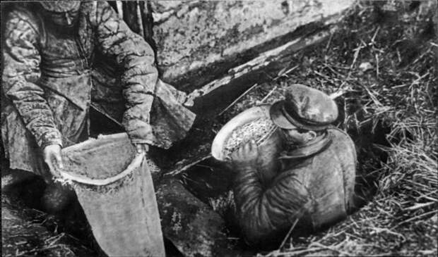 Работники ОГПУ извлекают из ямы спрятанное зерно (1932 год, фотография из Государственного музея политической истории России)