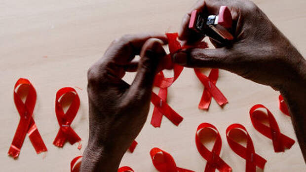 Мужчина делает красные ленточки, символ борьбы со СПИДом. Архивное фото