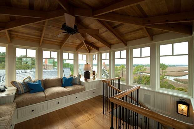 Отличный диванчик у окна под крышей дома, который станет любимым местом для отдыха.