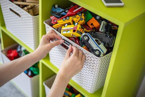 Person's hands organizing a toy bin. 