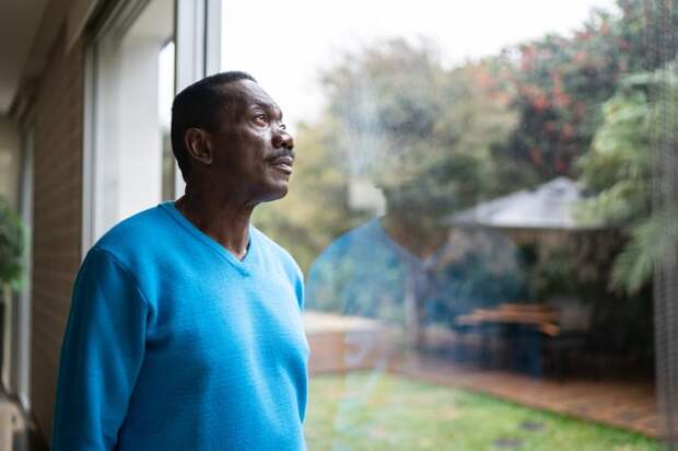 Person standing inside looking out a window.