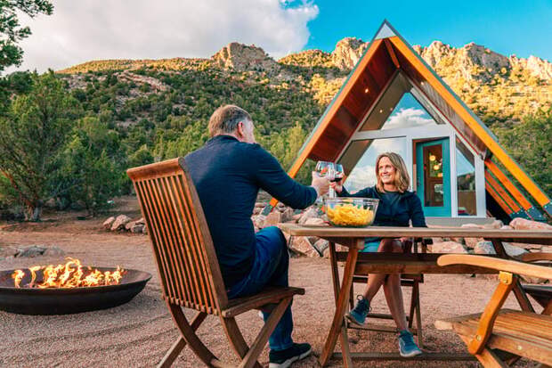 Smiling couple toasting over table outside cabin.