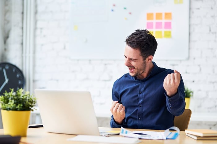 Man sitting at a desk celebrating with a fist pump