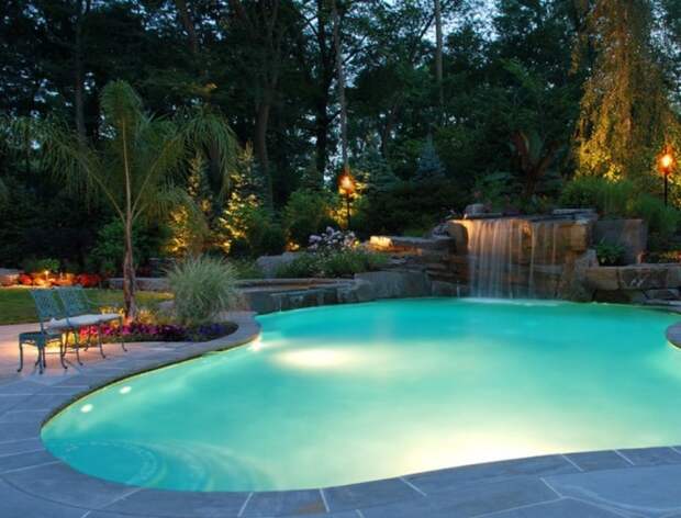 Плавательный бассейн оригинальной формы с необычным фонтаном и яркой подсветкой дна.