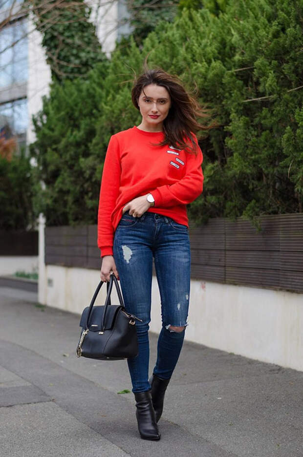 Девушка в синих джинсах и красном джемпере, черные ботильоны и сумка