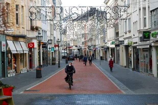 A man rides a bike through an almost deserted Sternstrasse (Star street) shopping street, as Germany goes back to a complete lockdown due to the coronavirus disease (COVID-19) outbreak, in Bonn, Germany, December 16, 2020. REUTERS/Wolfgang Rattay