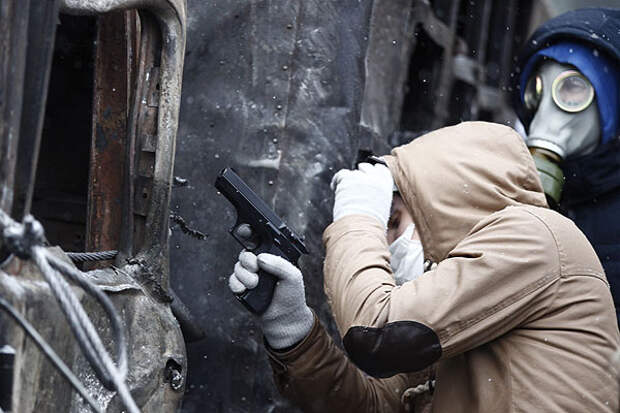 На фото двое участников киевских протестов: на одном - противогаз, в руках у другого - пневматический пистолет.