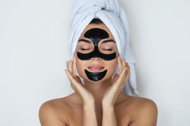 Young and beautiful woman with black peel-off mask on her face after shower