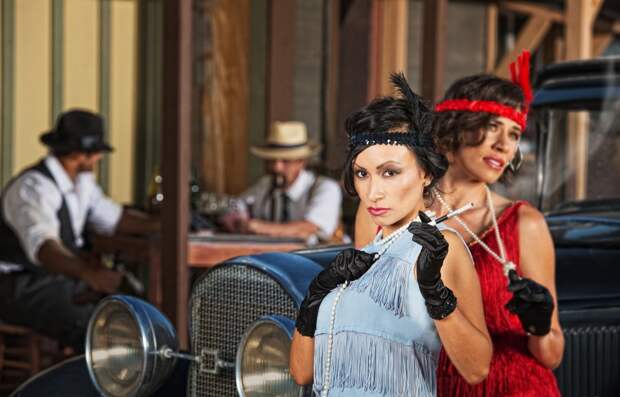 1920s flapper women near car and men in hats