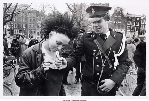 Полицейский даёт прикурить девушке–панку во время антиправительственной демонстрации в центре Амстердама, 1984 год, Нидерланды исторические фотографии, история, факты