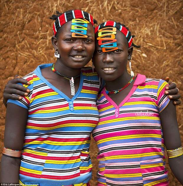 Девушки народа дасанеч позируют фотографу в ярких полосатых футболках с пёстрыми заколками в волосах и разноцветными браслетами на руках. Находчивые девушки способны смастерить модные аксессуары из чего угодно. 