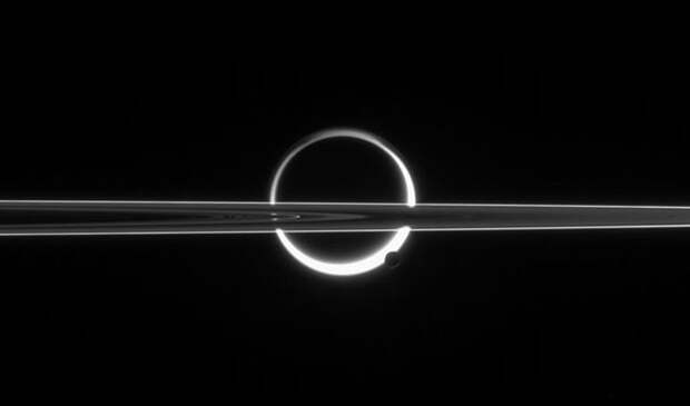 Кольца Сатурна, пересекающие Титан, недалеко от южного полюса которого виднеется Энцелад