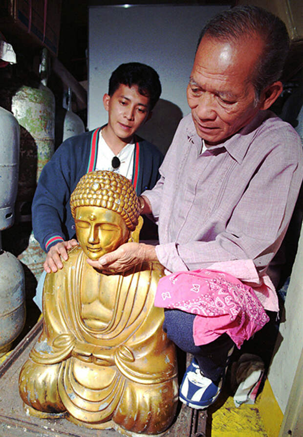 Сын Рогелио Рохаса со статуей Будды из бронзы и свинца. 1996 год