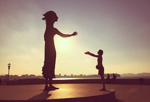 Статуя “Мать иммигранта” и иммигрантка из России на пляже Сан-Лоренсо в Хихоне, Астурия