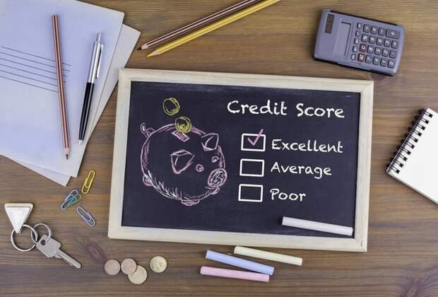 A desk with a chalkboard with drawing of a piggy bank and a checkmark next to Excellent Credit Score. 
