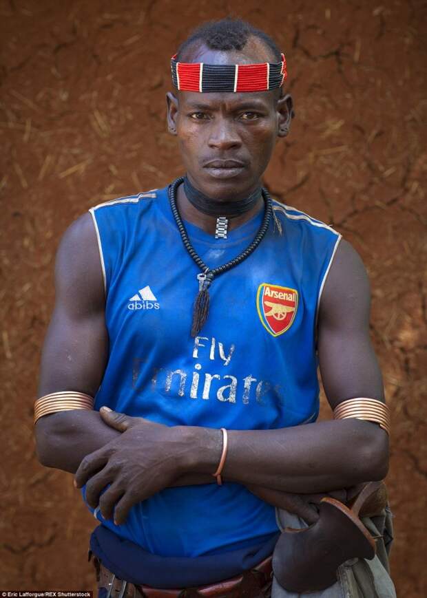 Мужчина народа дасанеч в футболке ФК «Арсенал». Подобные футболки пользуются популярностью у аборигенов благодаря ярким расцветкам и принтам, которые ассоциируются с их национальной одеждой. 