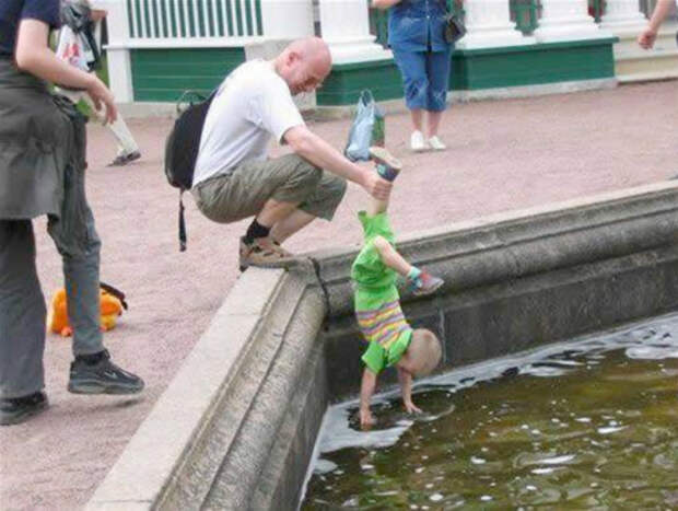 Заботливый отец помогает малышу собирать монетки из фонтана.