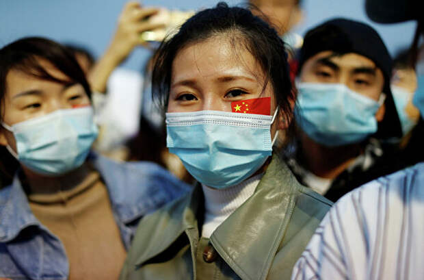 Люди в защитных масках на церемонии поднятия государственного флага на площади Тяньаньмэнь по случаю 71-й годовщины образования КНР в Пекине