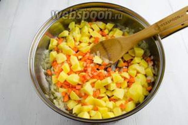 К луку добавить подготовленный картофель и морковь. Перемешать, 2 минуты подержать на среднем огне. 