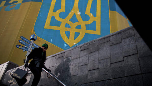 Женщина проходит мимо огромного украинского флага в центре Киева. Архивное фото Женщина проходит мимо огромного украинского флага в центре Киева. Архивное фото