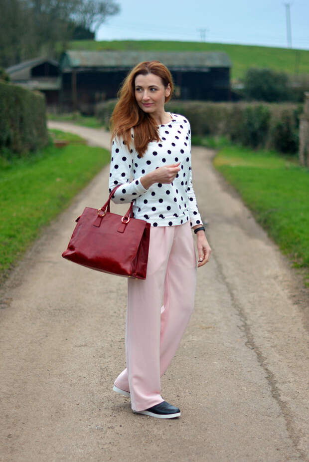 Black & white polka dot sweatshirt, pastel pink wide legged trousers, black slip on sneakers, cherry red tote