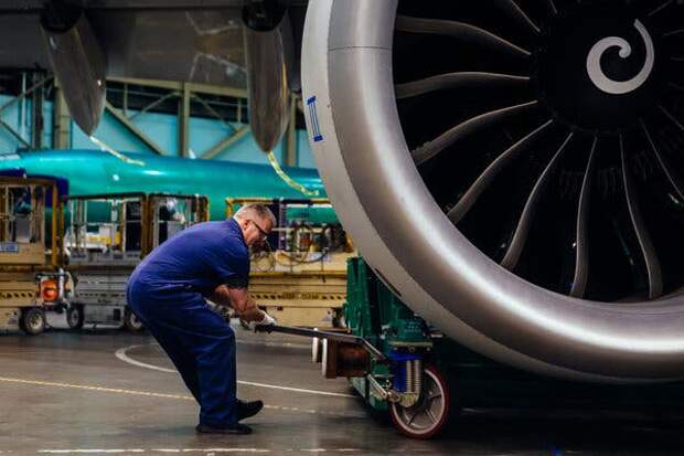 A worker adjusts the lift holding a General Electric engine being installed on a 747. 