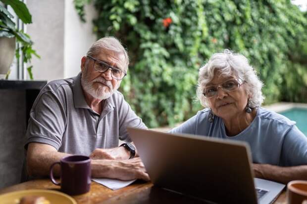 Two people with serious expressions at a laptop.