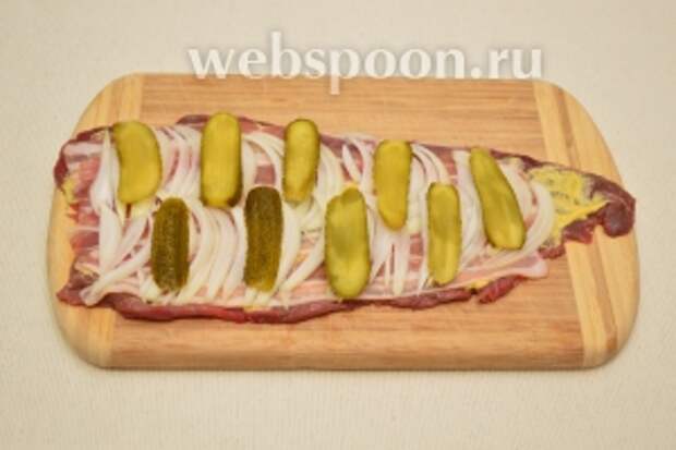 Поверх луковой прослойки уложить нарезанные огурцы. Выкладываем их не слишком близко друг к другу, иначе потом будет трудно заворачивать всё это хозяйство в рулет.