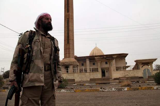 A volunteer from the Yazidi sect who have joined the Kurdish peshmerga forces stand in the street in the town of Sinjar