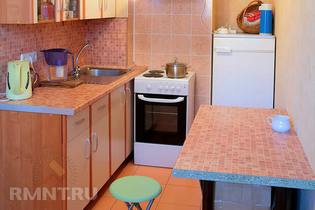 Планировка этой кухни позволила расположить холодильник в отдельной нише и оставить место для небольшого обеденного столика