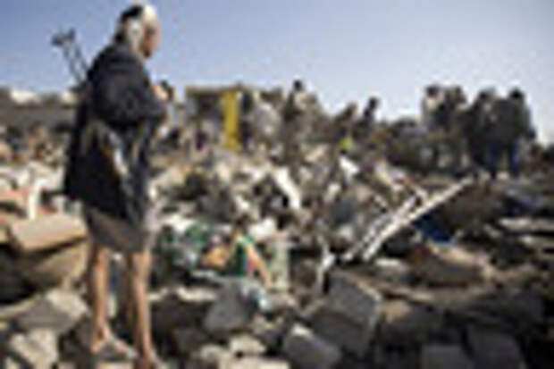A Houthi Shiite fighter stand guard as people search for survivors under the rubble of houses destroyed by Saudi airstrikes near Sanaa Airport, Yemen,
