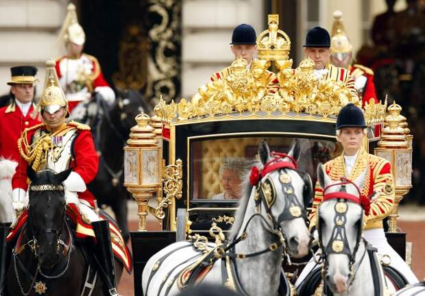 Церемония начинается с поездки Елизаветы II вместе с супругом принцем Филипом, герцогом Эдинбургским из Букингемского дворца в Вестминстерский дворец с эскортом конных гвардейцев. На фото: Елизавета II с супругом принцем Филипом, 2014 год 