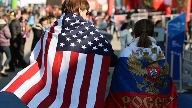 Молодые люди в национальных флагах США и России. Архивное фото Молодые люди в национальных флагах США и России. Архивное фото
