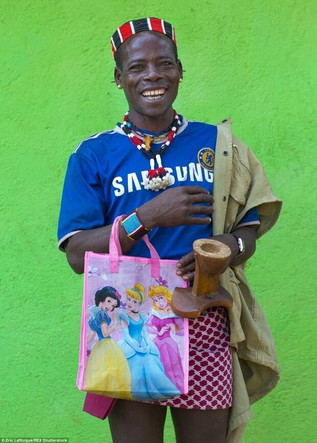 Мужчина народа дасанеч в футболке с эмблемой английского клуба «Челси» и с сумкой для покупок с диснеевскими принцессами. 