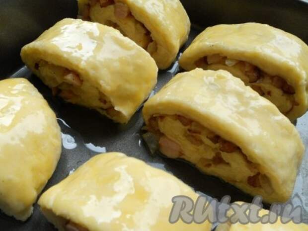 Форму для запекания смазать маслом, разместить в ней куски картофельного рулета, смазать сверху желтком. 