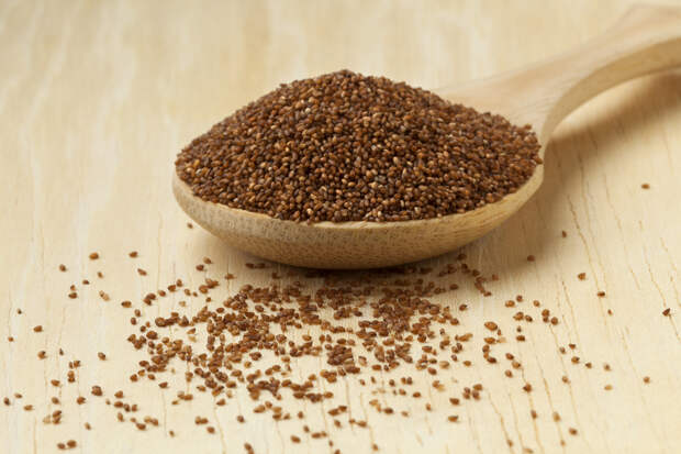 Heap of brown teff seeds on a wooden spoon