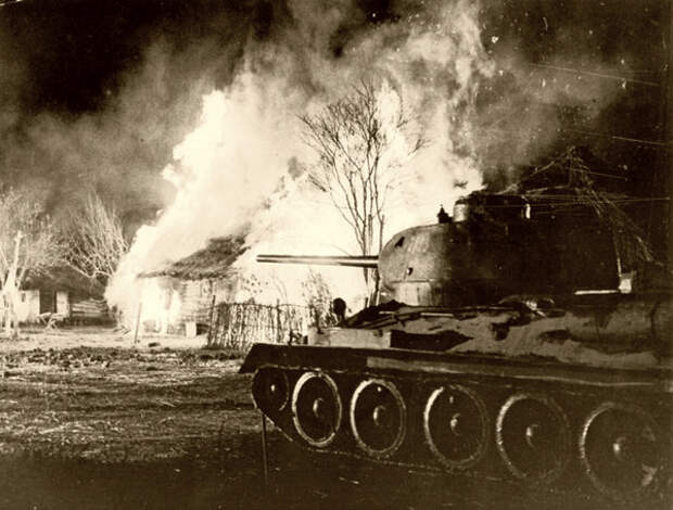 Советский танк Т-34-85 у охваченного огнем деревенского дома. 1944 г.
