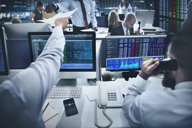 Stock trading room, with traders on the phone and sitting in front of monitors. 
