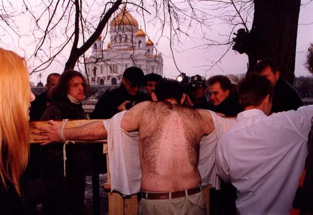 Олег Мавроматти распятый на кресте во время акции «Не верь глазам», 2000 год. 