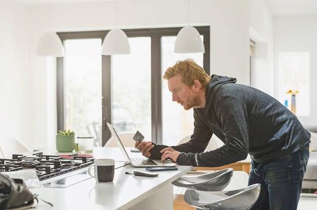 Man holding credit card and using laptop.