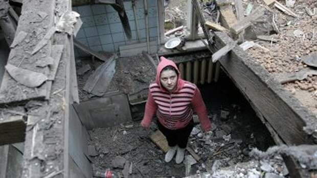 Женщина осматривает разрушенный дом после обстрела Донецка
