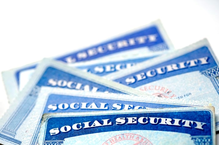 Two Social Security cards laid on top of a pile of cash.