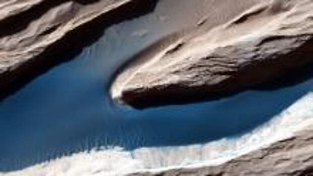 Although Mars isn't geologically active like Earth, surface features have been heavily shaped by wind. Wind-carved features such as these, called yardangs, are common on the Red Planet. On the sand, the wind forms ripples and small dunes. In Mars' thin atmosphere, light is not scattered much, so the shadows cast by the yardangs are sharp and dark.