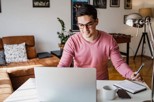 A smiling person at a laptop.