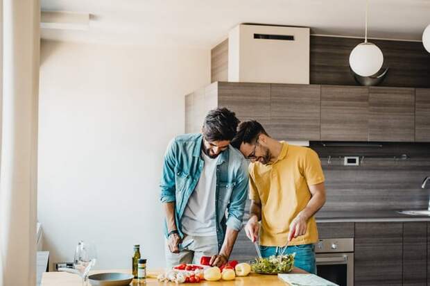 A happy couple laughing and cooking together in their kitchen.