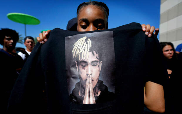 Anneyah Lawson, 14, of St. Petersburg, Fla., holds up a sweatshirt with an image of slain rapper XXXTentacion, before his memorial, in Sunrise, Fla. The rapper was gunned down in a luxury sports car last weekXXXTentacion Slain, Sunrise, USA - 27 Jun 2018