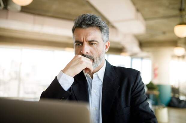 A person at a laptop with a serious expression.
