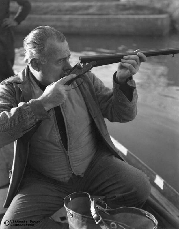 Известный американский писатель и журналист Эрнест Хемингуэй занят проверкой своего двуствольного ружья.